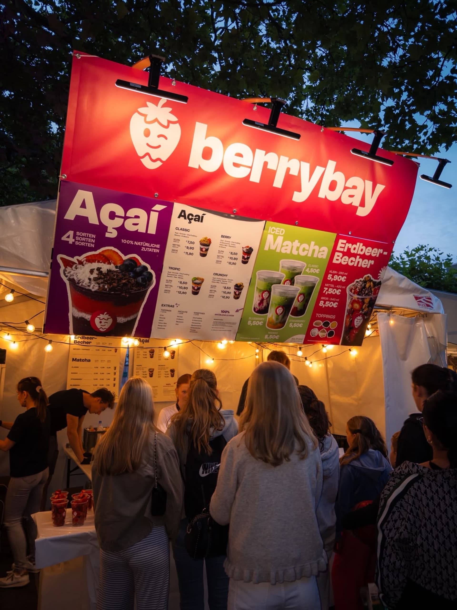 Der Berrybay-Marktstand am Abend mit Gästen davor